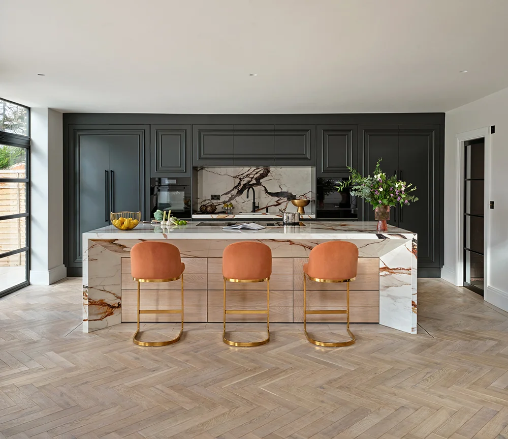 The Luxe Kitchen with charcoal cabinets, veined porcelain island and orange seating